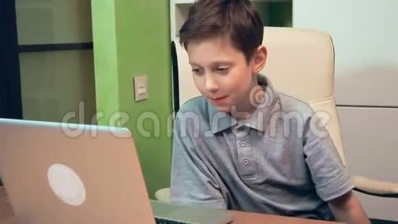 微笑的小男孩在笔记本电脑上播放视频视频的预览图