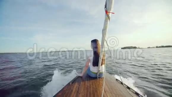 坐在游艇船尾的女孩快乐在海上旅行一位年轻的姑娘一头棕色长发视频的预览图