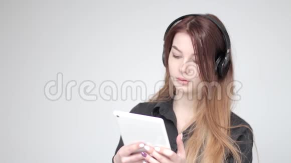 年轻漂亮的女士戴着白色平板电脑的耳机微笑着淡淡的背景视频的预览图