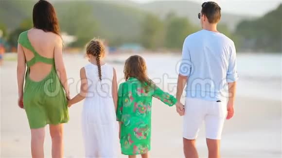 加勒比海度假时四口之家和两个孩子在海滩上散步视频的预览图
