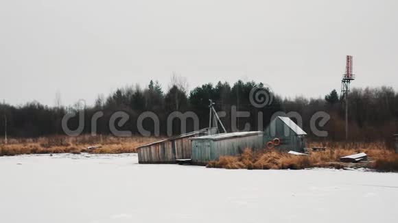 冰冷的湖岸上覆盖着白雪的木制渔夫小屋视频的预览图