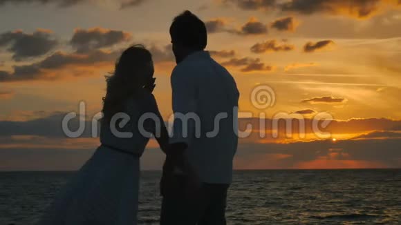 恋爱中的情侣享受大海的日落视频的预览图