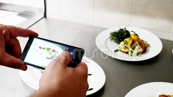 手机屏幕上有几道即食菜厨师在餐厅专业厨房拍摄食物视频的预览图