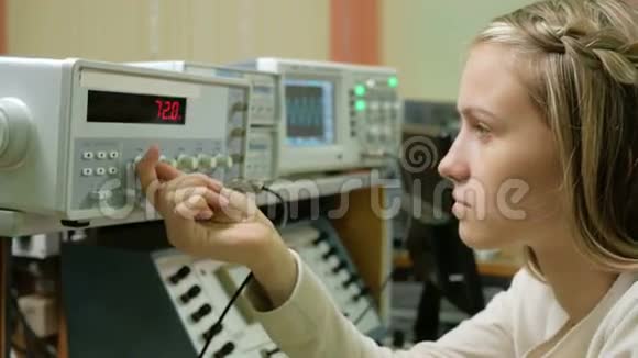 年轻的女工程师学生在实验室用电气仪器工作她小心翼翼地转动车轮时钟视频的预览图