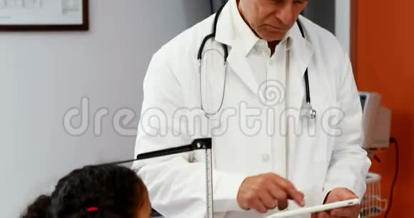 男性医生在测量女孩身高时使用数码平板电脑视频的预览图