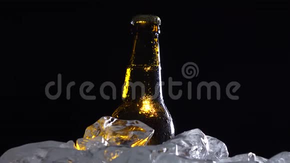 冰中的一瓶深色冷啤黑色背景剪影视频的预览图