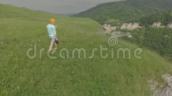 那个戴着眼镜和帽子的女摄影师带着她的dslr相机走在靠近悬崖的高原边缘视频的预览图