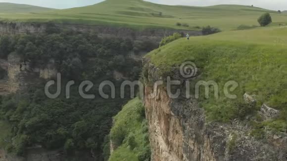 那个戴着眼镜和帽子的女摄影师带着她的dslr相机走在靠近悬崖的高原边缘视频的预览图