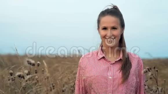 年轻漂亮的女人在金色的田野里摆姿势视频的预览图