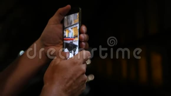 一个男人拿着电话和照片在一个黑暗的房间里特写镜头3840x21604公里视频的预览图