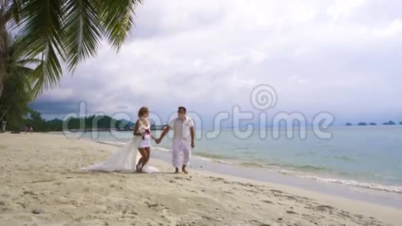 新郎新娘在沙滩上慢动作地玩得很开心新婚夫妇视频的预览图