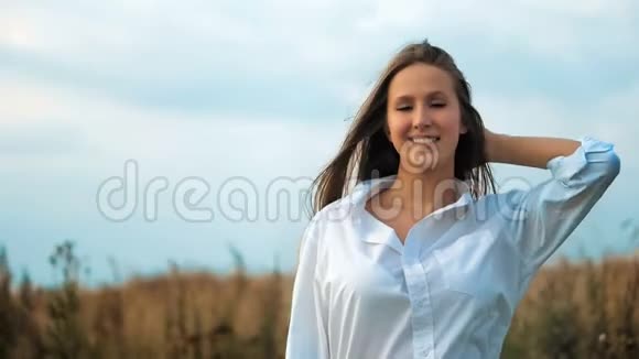 年轻漂亮的女人在金色的田野里摆姿势视频的预览图