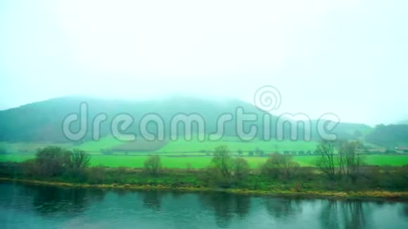 秋天从路过的火车窗口可以看到雾河和绿野中的美丽景色视频的预览图