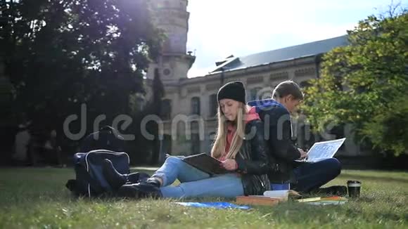 年轻的学生夫妇在公园草坪上学习视频的预览图