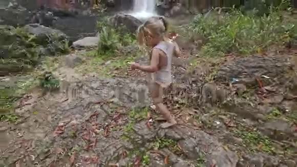 小女孩在石面上与高瀑布级联视频的预览图