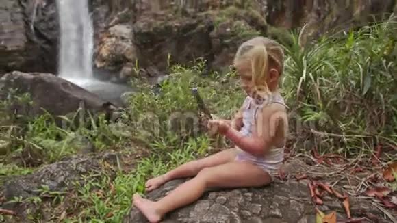 特写小女孩用电话在瀑布做自拍视频的预览图