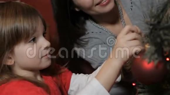 女人和小女孩把装饰品挂在圣诞树上视频的预览图