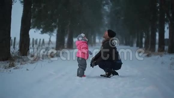 父亲和他的小女儿在公园里享受冬天下的雪视频的预览图