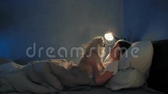 男孩晚上在床上休息和他的狗玩耍视频的预览图