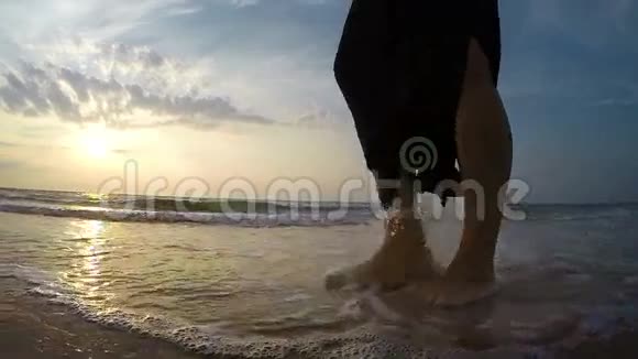 日落时分一个女人脚踩在沙滩上的慢镜头视频的预览图