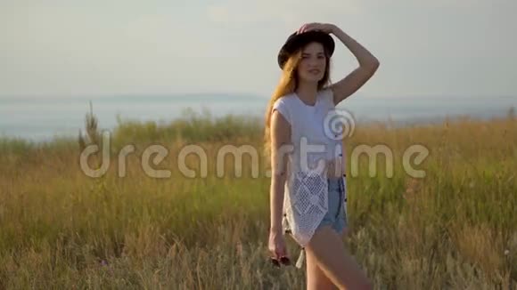 年轻漂亮的模特戴着帽子站在河边的悬崖边上视频的预览图