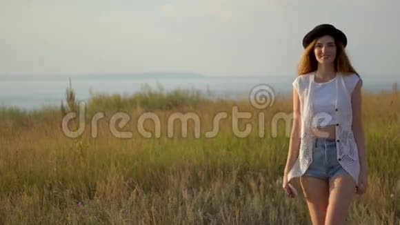 年轻漂亮的模特戴着帽子站在河边的悬崖边上视频的预览图