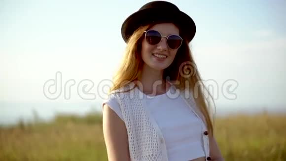 年轻漂亮的女模特戴着帽子戴着太阳镜摆出户外慢动作视频的预览图