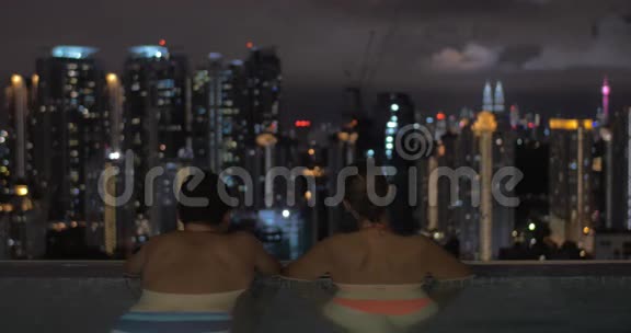 马来西亚吉隆坡一家酒店的屋顶上有一个游泳池男人和女人一起去夜城视频的预览图