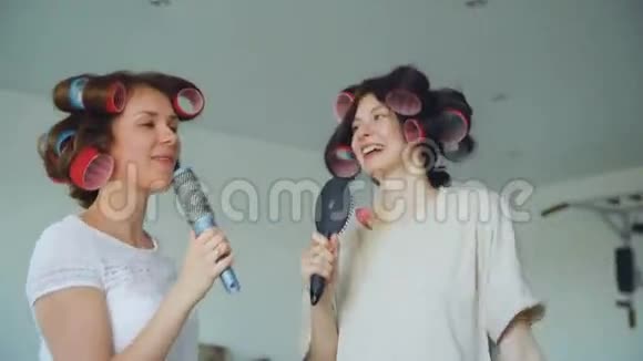两个有趣的女孩用梳子跳舞唱歌在家里的客厅里玩得很开心视频的预览图
