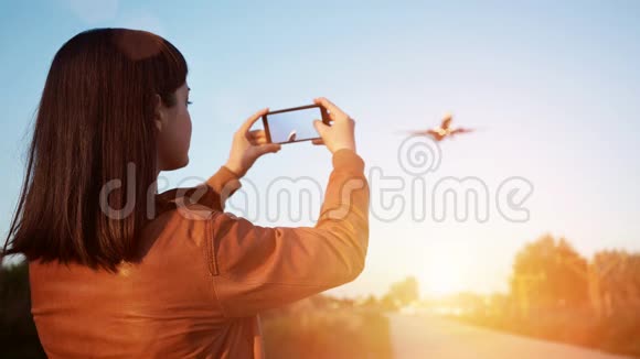 手握智能手机的折叠式电影机同时录制飞机着陆视频视频的预览图