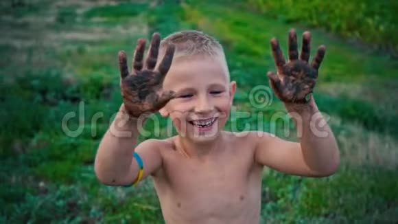 一个快乐的孩子从泥土中露出肮脏的双手一个涂抹在泥土中的男孩一种快乐的童年消遣视频的预览图