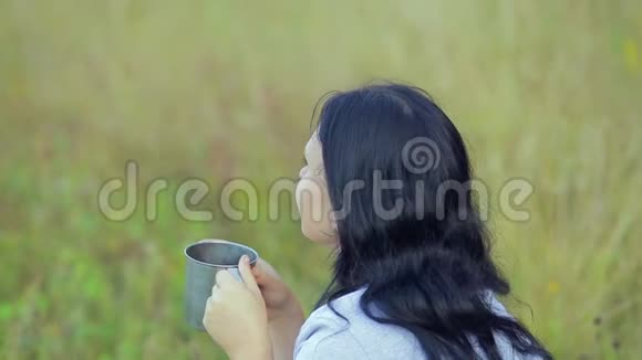 一个年轻的黑发女人正在喝一杯茶视频的预览图