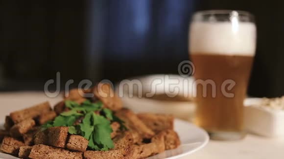 黑桌子上盘子里放着啤酒和零食的杯子视频的预览图