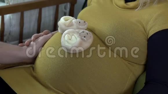 在未来妈妈的肚子上近距离拍摄老鼠宝宝鞋视频的预览图