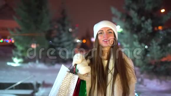 概念圣诞购物美丽的女人手里拿着多种颜色的包裹晚上散步过圣诞节视频的预览图