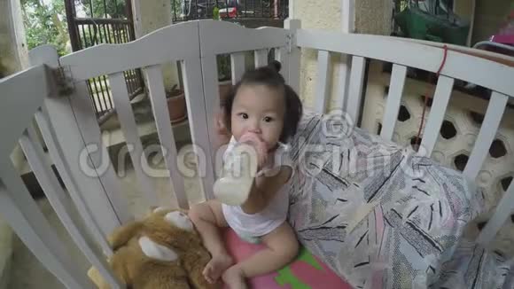 小女孩在婴儿床上奶瓶喂养自己视频的预览图