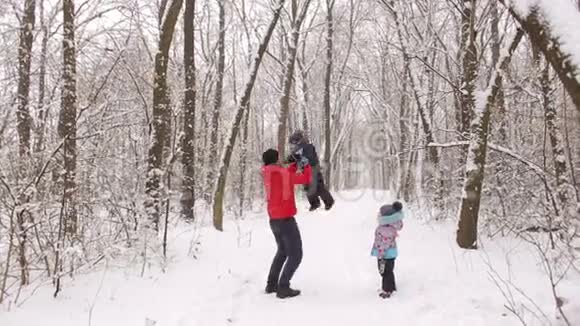 爸爸和两个孩子在冬天的森林里玩耍视频的预览图