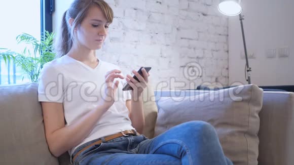女人在智能手机上浏览互联网坐在沙发上视频的预览图