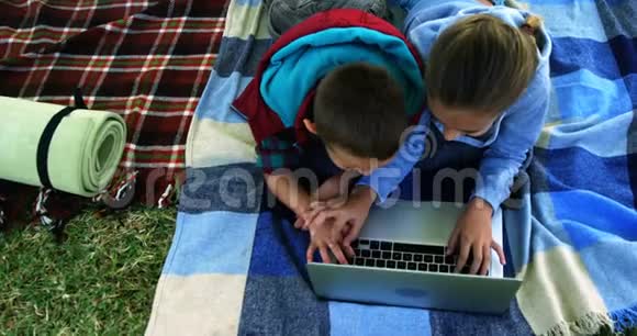 在营地帐篷外使用笔记本电脑的小兄弟视频的预览图