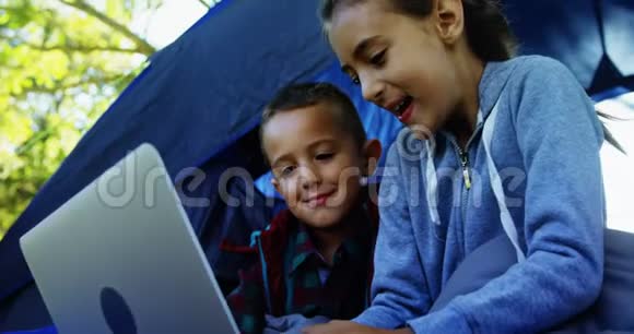在营地帐篷外使用笔记本电脑的小兄弟视频的预览图