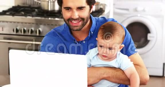 快乐的父亲抱着他的孩子用笔记本电脑视频的预览图