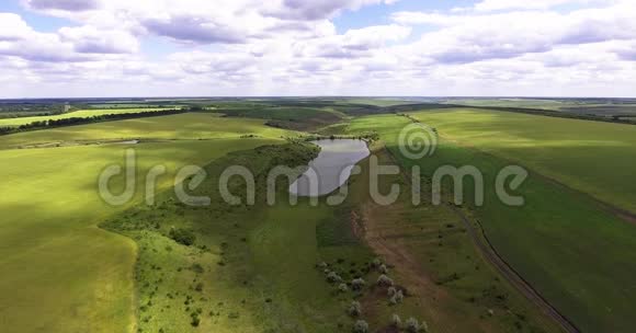 夏季乡村的鸟瞰图在绿色的田野和宁静的湖上飞行视频的预览图