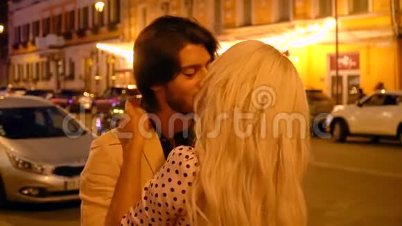 浪漫的情侣在夜晚城市的灯笼和橱窗展示的背景下拥抱和亲吻视频的预览图