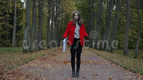 美丽的白种人女人穿着红色外套在秋天的森林里用纸出售标语牌视频的预览图