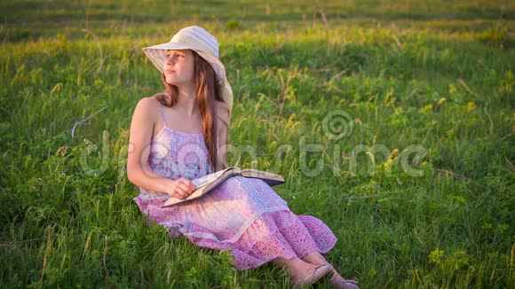 浪漫的女孩在绿色草地上看书视频的预览图