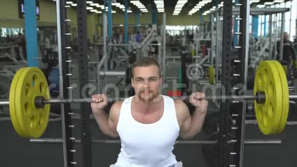 健身房的力量训练用杠铃做蹲的家伙健美运动员用杠铃做运动视频的预览图