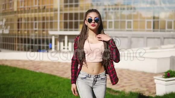 年轻漂亮的女孩带着恐惧在公园里跳舞穿着牛仔裤和太阳镜听音乐和音乐的漂亮女人视频的预览图