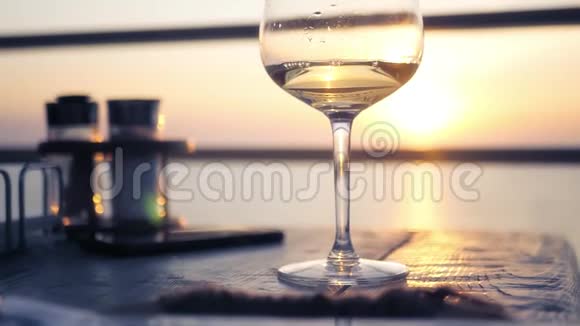 桌上放着一杯白葡萄酒背景是夕阳和地平线上的大海高清1920x1080视频的预览图