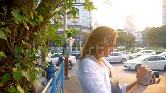 一个拿着相机的女人走过一个现代化的大城市的街道视频的预览图
