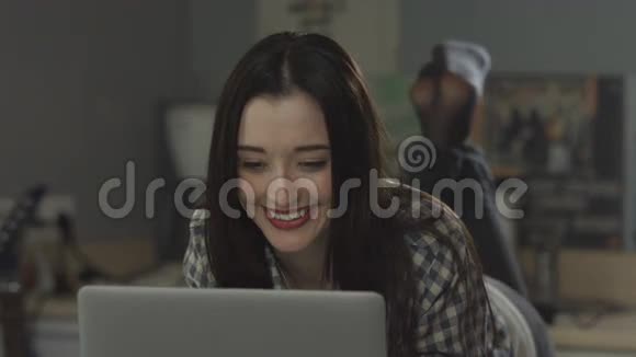 美丽的女孩躺在床上看着一台笔记本电脑视频的预览图